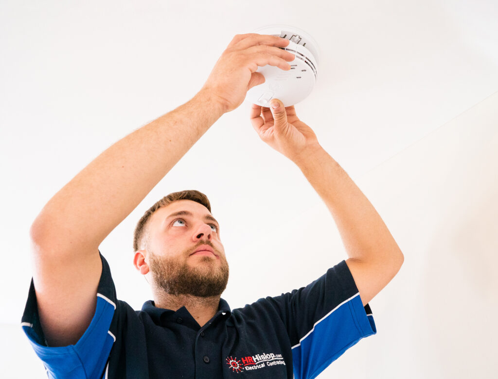 Picture of an electrician securing a smoke alarm.